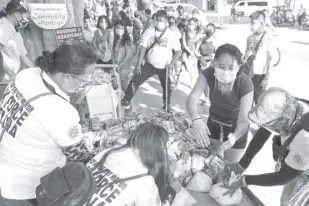  ?? AP/AARON FAVILA ?? ANA PATRICIA NON, second from right, arranges donated food with village workers before they distribute it at a makeshift stall called “Community Pantry” beside a road in Quezon City, Philippine­s, on Monday, April 19, 2021. Non started the Community Pantry in Maginhawa Street by placing food on a makeshift stall for people who need it as many have lost jobs due to quarantine measures set by the government to curb the surge in Covid-19 cases in the country. The theme “Give what you can, take what you need” has spread to several communitie­s which have placed their own makeshift stalls to support people struggling to make ends meet.