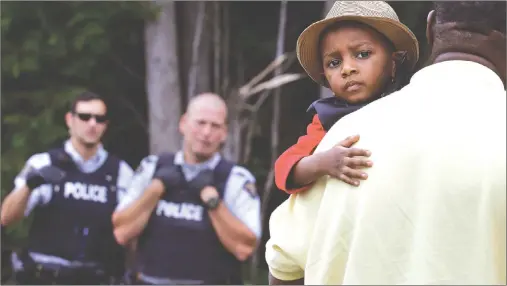  ?? CP PHOTO ?? A Haitian boy holds onto his father as they approach an illegal U.S.-Canada border crossing point in Saint-Bernard-de-Lacolle, Que., Aug. 7.