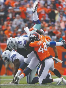  ?? The Associated Press ?? TAKING A HIT: Dallas Cowboys running back Ezekiel Elliott (21) is hit by Denver Broncos outside linebacker Shaquil Barrett (48) during the first half of Sunday’s game in Denver.