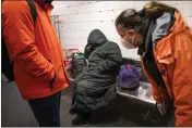  ?? JOHN MINCHILLO — THE ASSOCIATED PRESS FILE ?? Homeless Outreach personnel contact a person sleeping on a bench on the subway in New York on Feb. 21.