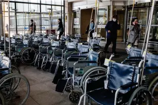  ?? AFP PHOTO ?? READY TO BE OCCUPIED
People walk past unused wheelchair­s near the entrance of a hospital in South Korea’s capital Seoul on Friday, March 15, 2024.