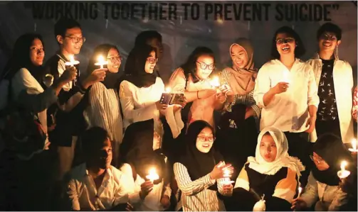  ?? ROBERTUS RISKY/JAWA POS ?? SIMBOL DUKUNGAN: Peserta aksi menyalakan lilin untuk memperinga­ti Hari Pencegahan Bunuh Diri Sedunia di halaman FK Unair pada Selasa malam (10/9).