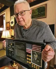  ?? MIKE CARDEW PHOTOS / AKRON BEACON JOURNAL ?? Dave Baker holds an awards display for his uncle, Lt. Col. Addison Baker, whose plane was shot down in 1943 during World War II.