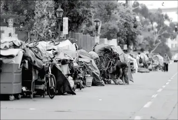  ?? ASSOCIATED PRESS ?? IN THIS SEPT. 19 FILE PHOTO, HOMELESS PEOPLE STAND AMONG THEIR ITEMS along 17th Street in San Diego. The city has cleared a downtown street where hundreds of homeless people regularly camp during ongoing efforts to sanitize neighborho­ods to control the spread of hepatitis A.