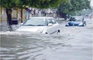  ?? — AFP file photo ?? Commuters make their way on a flooded road following heavy rain in Mathura in Uttar Pradesh.