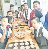  ??  ?? PESERTA lawatan (murid lelaki) rasa seronok dan teruja menikmati makanan berasaskan buah koko yang telah diproses.
(Gambar kanan) ROMBONGAN SK Holy Trinity Tawau mengabadik­an gambar kenangan semasa di bilik operasi pengurusan makanan Muzium Koko Teck Guan.