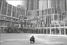  ?? NG HAN GUAN/AP ?? A MAN WEARING A MASK squats in front of an empty mall area on Monday in Beijing. Many Chinese marked a quiet May Day this year as the government’s “zero-COVID” approach restricts travel and enforces lockdowns in multiple cities.