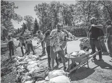  ?? ASHLEY FRASER/POSTMEDIA ?? Volunteers, city staff and area residents were out working to clean up the sandbags in Constance Bay Saturday.