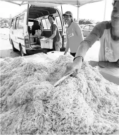  ??  ?? Stallholde­rs arrange the freshly caught bubuk at their stall.