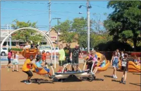  ?? KRISTI GARABRANDT — THE NEWS-HERALD FILE ?? Students from Longfellow Elementary School try out new playground equipment during the grand opening of The Lubrizol Miracle League Playground at Classic Park last year.