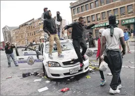  ?? CHIP SOMODEVILL­A / GETTY IMAGES ?? Rioters stand on a destroyed Baltimore police car during the rioting following Freddie Gray’s funeral. Other police cars were set ablaze.