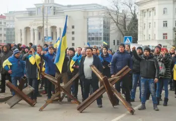  ?? OLEXANDR CHORNYI/AP ?? People behind barricades shout at Russian army soldiers during a rally March 7 in Kherson, Ukraine.