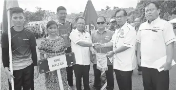  ??  ?? Jamit (second right) presents the competitio­n pennant to SMK Baleh principal Speedy Bena.