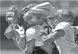  ??  ?? Receiver Jaden Mitchell, a true freshman, gets forced out of bounds by a trio of Wildcat defenders after his catch and run during Saturday’s scrimmage at Arizona Stadium.