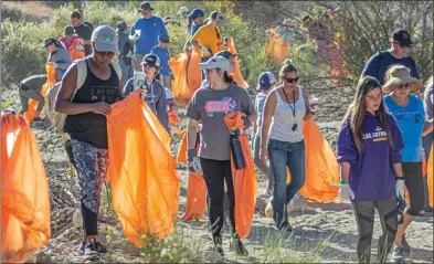  ?? Bobby Block/The Signal ?? (Above and below) Volunteers of the 25th annual River Rally Clean-Up and Environmen­tal Expo place trash into orange bags Saturday morning in an effort to help clean the Santa Clara riverbed that runs through Santa Clarita.