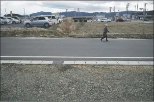  ?? (AP Photo/Eugene Hoshiko) ?? A woman walks through Minamisanr­iku on Saturday, nearly 10 years after the tsunami.