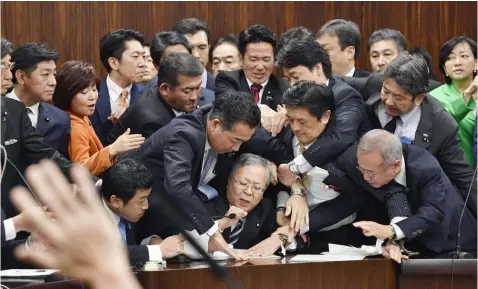  ??  ?? Japan’s opposition parties’ members try to stop Judicial Affairs Committee Chairman Shinichi Yokoyama, bottom center, from moving to hold a vote for a bill to revise an immigratio­n control law, at upper house committee in Tokyo early Saturday, Dec. 8, 2018. Japan is preparing to officially open the door to foreign workers to do unskilled jobs and possibly eventually become citizens. (Kyodo News via AP)