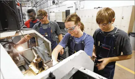  ?? TY GREENLEES / STAFF ?? Miami Valley Career Technology Center precision-machining students (from left) William Stephens, Tyler Pleiman, Sarah Virag and Troy Wolfe set up a CNC lathe. The seniors are training for machinist jobs that are in high demand in the region.