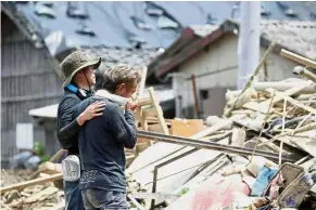  ?? — AP ?? Devastatin­g loss: A man comforting his friend as they survey the ruins of homes in Uwajima, Ehime prefecture.