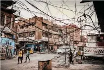  ?? Sergey Ponomarev/New York Times file photo ?? Residents of Baghdad walk under electrical wires. Iraq struggles with persistent electricit­y shortages.