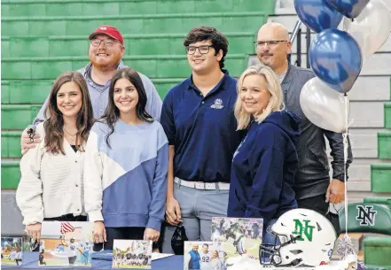  ??  ?? Pierce Hassen, center, smiles with his family after Signing Day ceremonies at Norman North High school. The defensive lineman missed all of his junior season after a car accident caused serious injury to his left hand, but extensive physical therapy, thickly padded gloves and high pain tolerance got him back on the field this past season. [CHRIS LANDSBERGE­R/ THE OKLAHOMAN]