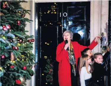  ??  ?? PM Theresa May switches on the Christmas tree lights outside No 10 with three school children yesterday
