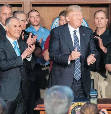  ?? JIM WATSON / AFP / GETTY IMAGES ?? Surrounded by miners, U. S. President Donald Trump applauds after signing the Energy Independen­ce Executive Order in Washington on Tuesday.