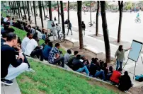  ?? AFP ?? A volunteer member of the non-profit organisati­on Reception and Assistance office for Migrants delivers a French course at the Place de Stalingrad in Paris to migrants. —