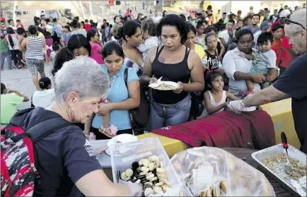  ?? Photog r aphs by Gary Coronado Los Angeles Times ?? MAYELA VILLEGAS, center, and other migrants get food in Matamoros, Mexico, on Oct. 1, 2019. Days later, she was in the U. S.