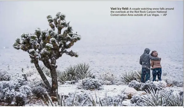  ?? — AP ?? Vast icy field: A couple watching snow falls around the overlook at the Red Rock Canyon National Conservati­on Area outside of Las Vegas.