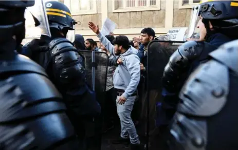  ?? LIONEL BONAVENTUR­E/AFP/GETTY IMAGES ?? A man gestures in front of a line of riot police in a Paris street on Monday during a police operation at a makeshift migrant camp.