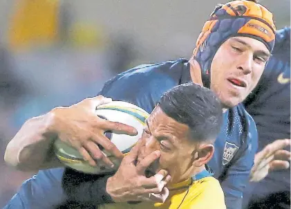  ?? AP ?? Juego de manos. El segund línea Petti trata de bajar al fullback Folau, autor de dos tries.