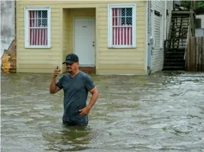  ?? Associated Press ?? ■ Barry Williams talks to a friend on a phone Saturday as he wades through storm surge from Lake Pontchartr­ain in Mandeville, La.