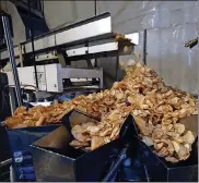  ?? TY GREENLEES / STAFF ?? Freshly seasoned potato chips tumble into the bagging machine at Mikesell’s.
