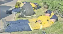  ??  ?? EXHAUSTION: Firefighte­rs manage to catch naps out in the open Friday after working some 20 hours straight.