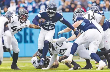  ?? AP PHOTO/WADE PAYNE ?? Tennessee Titans running back Derrick Henry carries the ball as he escapes Jacksonvil­le Jaguars tackle DaVon Hamilton and other defenders during Sunday’s AFC South Division matchup in Nashville. Henry rushed for 153 yards and a touchdown in what might have been the final game of his Titans career, leading the team to a 28-20 victory that keeps the Jaguars out of the playoffs. Henry’s contract is up, and the two-time NFL rushing champion could become a free agent in March.