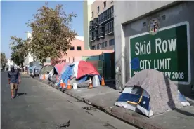  ?? Photograph: Lucy Nicholson/Reuters ?? A man walks by the Skid Row area in Los Angeles, where there are many homeless encampment­s.