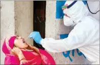  ?? PTI ?? A medic takes a swab sample of a woman for COVID-19 test at a camp set up in Loha Khan area, in Ajmer, on Wednesday