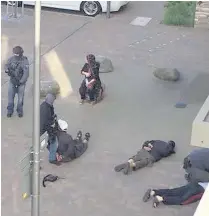  ??  ?? > People lie on the ground after being detained by police at Elizabeth Fry flats in Barking, east London, which officers raided following the attack