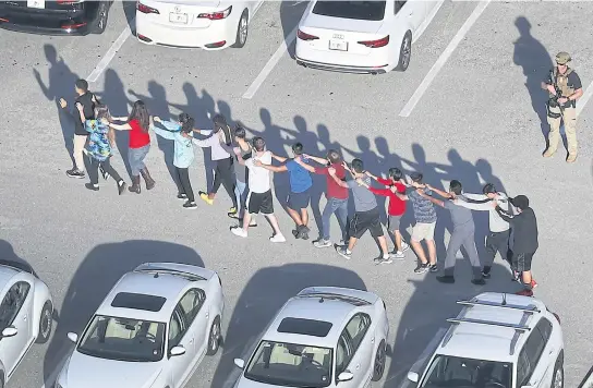  ??  ?? People are brought out of the Marjory Stoneman Douglas High School after a shooting that killed 17 people on Wednesday.