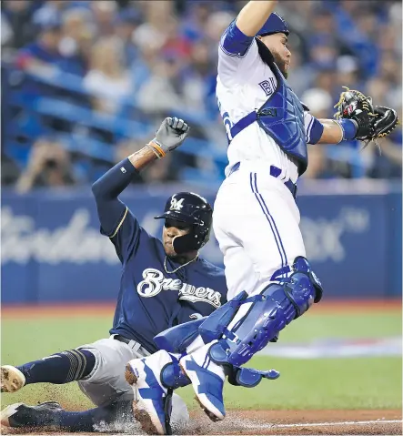  ?? FRANK GUNN / THE CANADIAN PRESS ?? Milwaukee Brewers centre fielder Keon Broxton slides safely into home past Toronto Blue Jays catcher Russell Martin to score in Toronto’s home opener Tuesday at Rogers Centre.