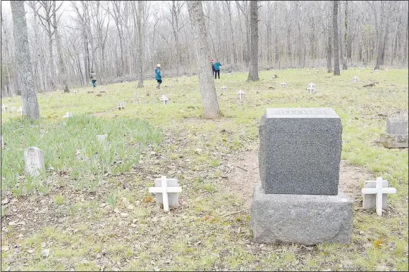 ?? (NWA Democrat-Gazette/Rachel Dickerson) ?? Martha Jane Beavers’ headstone (at right) is shown April 16 in the Beavers Cemetery. The cemetery is dotted with small white crosses. In the background, patrons on the Bella Vista Historical Society cemetery tour visit the cemetery.