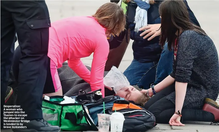  ??  ?? Desperatio­n: A woman who jumped into the Thames to escape the attacker on Westminste­r Bridge is tended to by brave bystanders