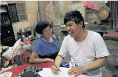  ??  ?? Chen Hong-zhi quarrels with his stepmother Wang Miao-cyong, 65, while writing his notes at his home in Hsinchu.