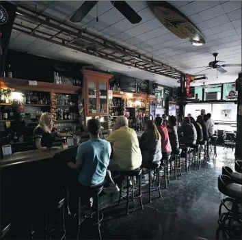  ?? Ezra Shaw Getty Images ?? CATHY SANCHEZ tends bar at Town Square in Sonoma, Calif., where the lights were out because of a power shut-off by Pacific Gas & Electric. The utility’s chief executive said he made the right call on outages.