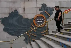  ?? (AP) ?? A woman walks by a map showing Evergrande developmen­t projects in China, as she heads to an Evergrande city plaza in Beijing.