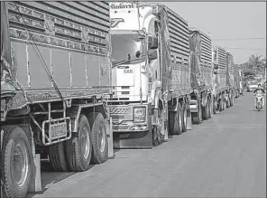  ?? The New York Times/OMAR HAVANA ?? Dozens of trucks filled with dried cassava chips line up on the side of a road in Malai, Cambodia, ready to carry their loads across the border into Thailand.