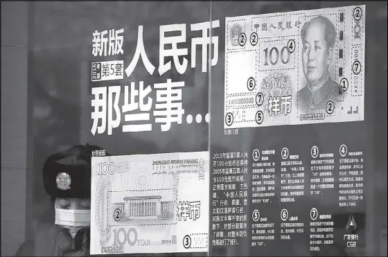  ??  ?? A security guard wearing a protection mask against air pollution takes a rest near a bank window panel displaying the security markers on the latest yuan note in Beijing. The Chinese government says it will ease restrictio­ns on foreign investment in...