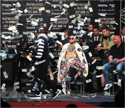  ??  ?? SHOW ME THE MONEY: Dollar bills rain down on Conor McGregor during a press conference with Floyd Mayweather Jr