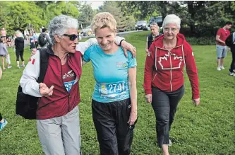 ?? MARTA IWANEK
THE CANADIAN PRESS ?? Ontario Liberal Leader Kathleen Wynne talks with a supporter at the Toronto Women's Run Series held at Wilket Creek Park in Toronto on Sunday. Wynne’s partner, Jane Rounthwait­e, right, walks with them.